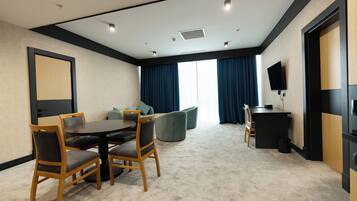 A conference room with a round table, four chairs, a sofa, a TV, and a large window with curtains.