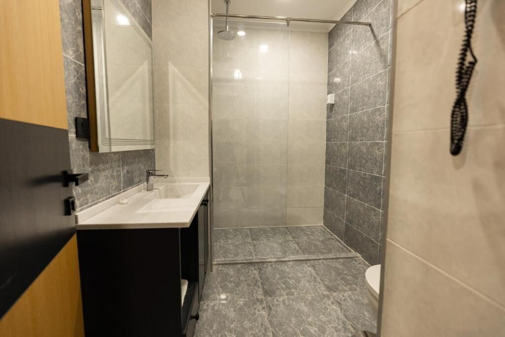 Un baño moderno con ducha de mampara de vidrio, lavamanos y retrete.