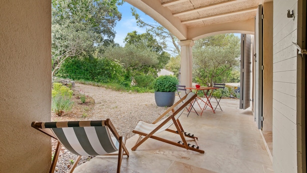 A covered outdoor area with a pergola, a striped lounge chair, a folding chair, a potted plant, and a table with chairs. - Guest Room 'Chambre 2 Chine' with Shared Pool, Wi-Fi, and Air Conditioning (Cotignac)