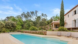 A swimming pool with a stone wall, lounge chairs, and a building with a tiled roof. - Guest Room 'Chambre 2 Chine' with Shared Pool, Wi-Fi, and Air Conditioning (Cotignac)