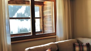 Una habitación acogedora con una ventana de madera, un sofá beige y cojines a cuadros.