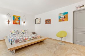 A bedroom with a bed, a chair, and wall art. - Guest Room “Room 1 Rd” with Shared Pool, Wi-Fi, and Air Conditioning (Cotignac)