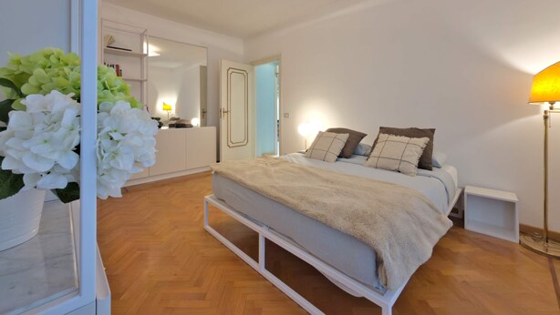 Ein Schlafzimmer mit einem Bett, Nachttischen, einem Spiegel und einer Pendelleuchte.