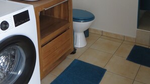 Ein kleines Badezimmer mit Waschmaschine, Waschbecken, Toilette und Spiegel.