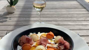 Une table à manger avec une assiette de nourriture et un verre de vin blanc.