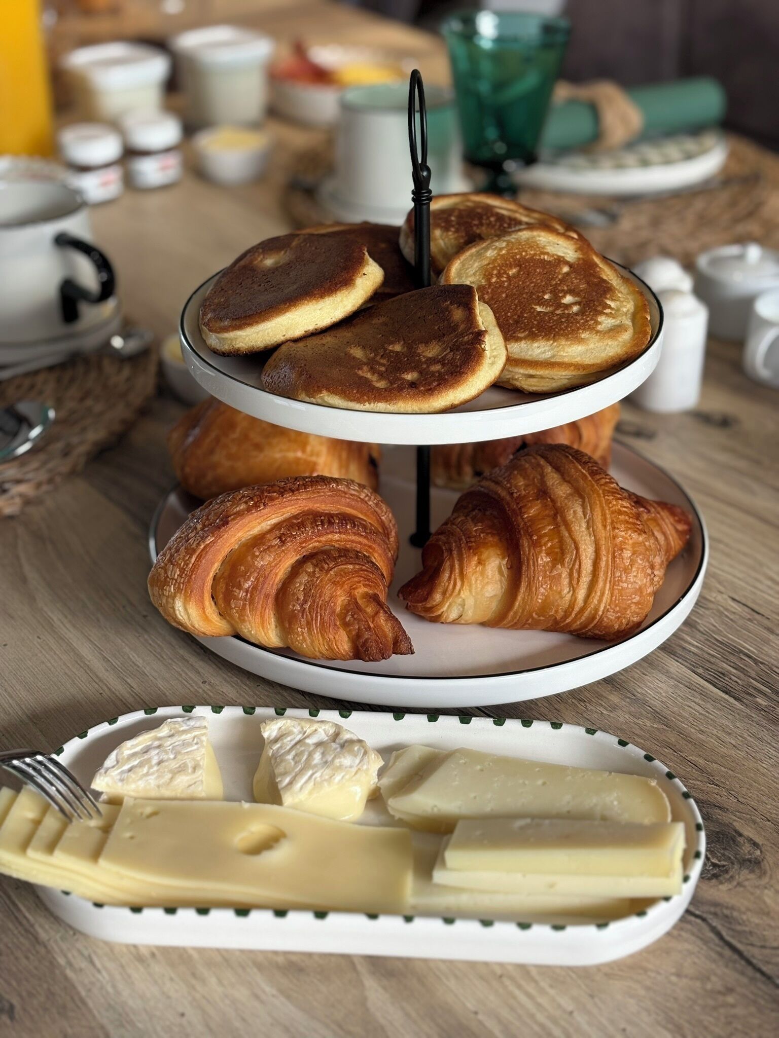 Desayuno con tortitas, cruasanes y queso sobre una mesa de madera.
