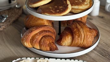 Desayuno con tortitas, cruasanes y queso sobre una mesa de madera.