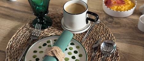 Disposição para o café da manhã com prato, guardanapo, xícara e talheres sobre um tapete trançado.