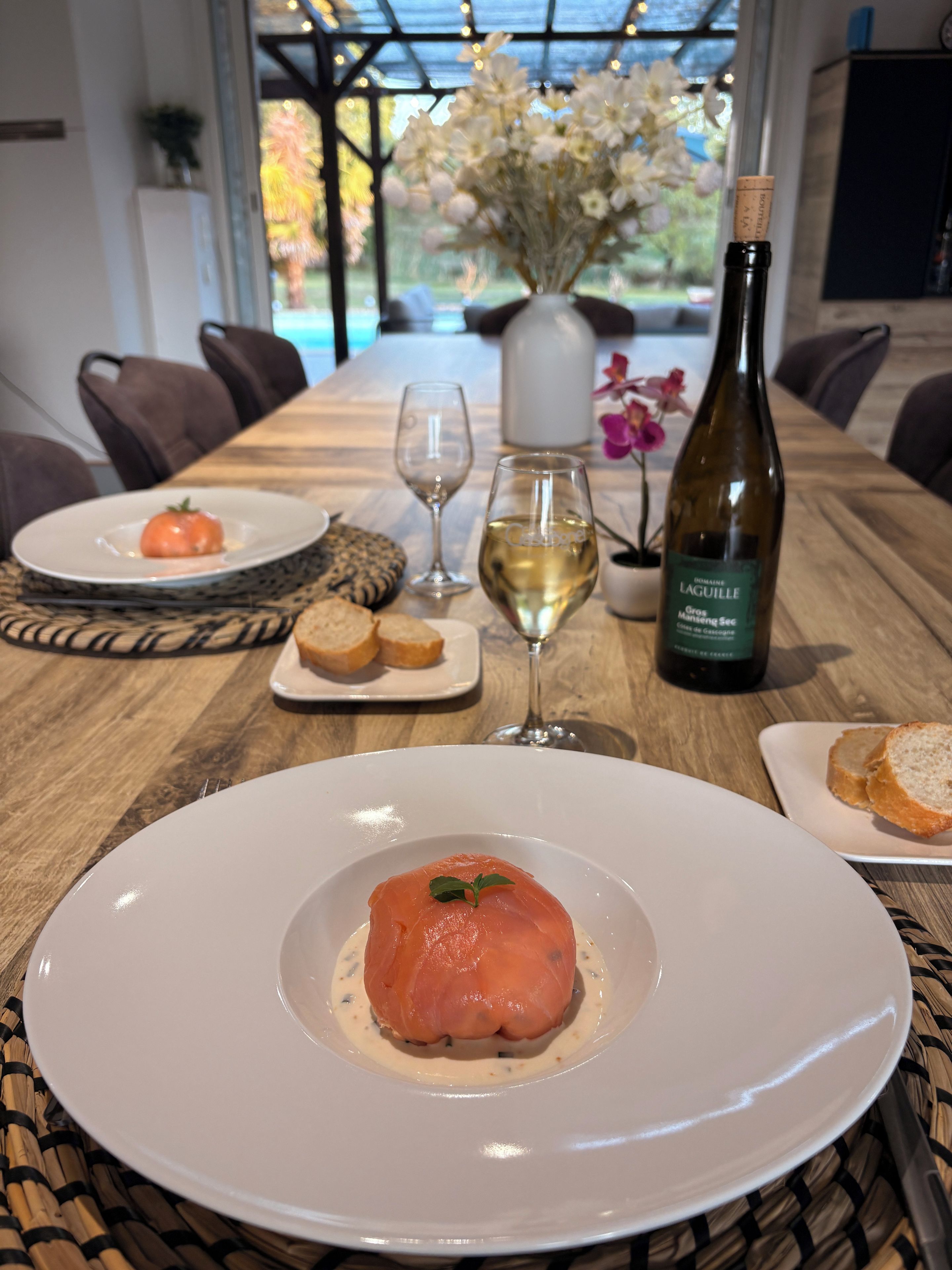 Une table à manger avec une bouteille de vin, des verres et des assiettes remplies de nourriture.