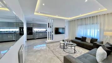 A modern living room with a grey sofa, a coffee table, and a TV mounted on the wall.