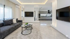 Een moderne woonkamer met een bank, een salontafel en een aan de muur bevestigde televisie.