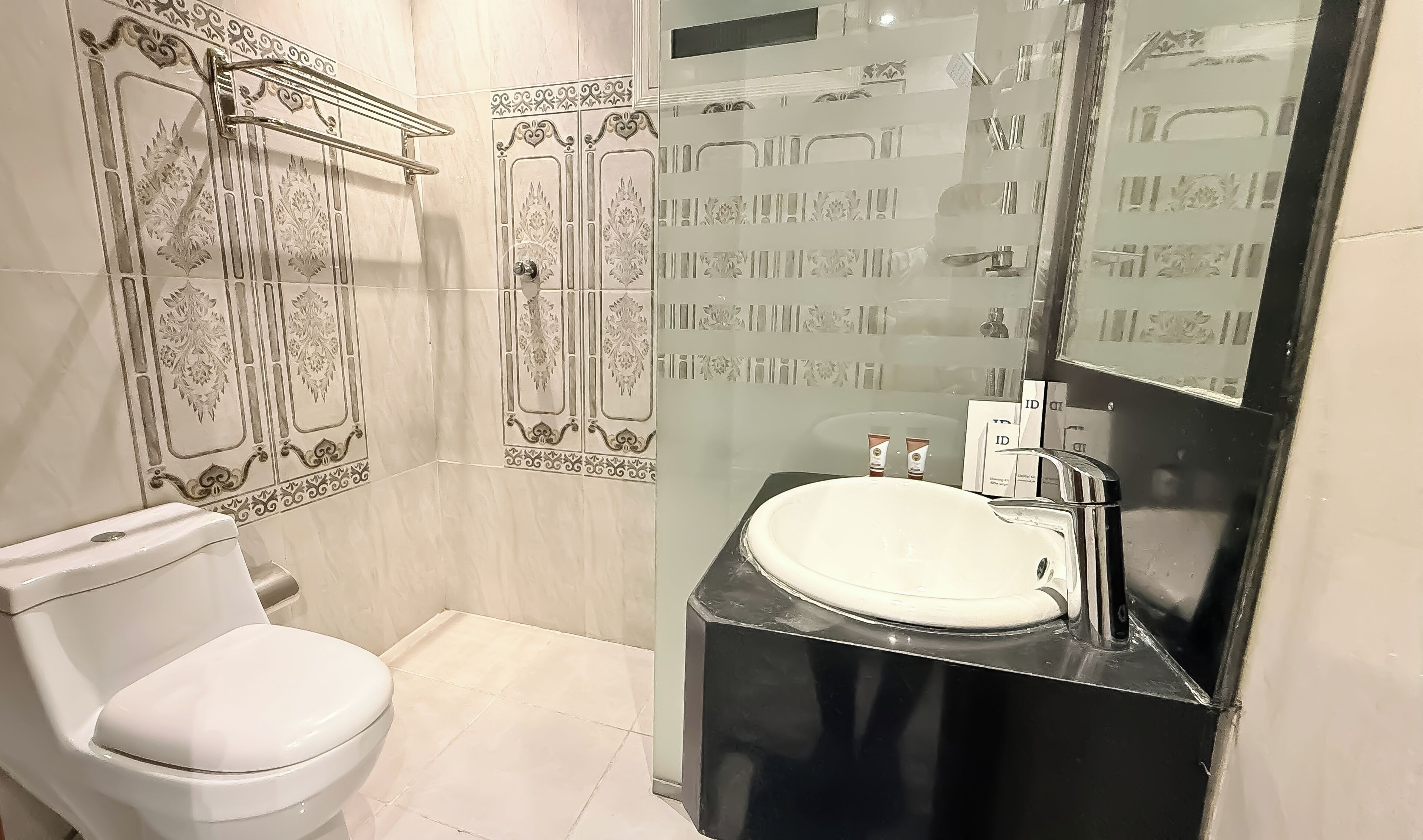 Ein Badezimmer mit einer weißen Toilette, einem schwarzen Waschbecken und einem Spiegel mit einer Glasabdeckung.