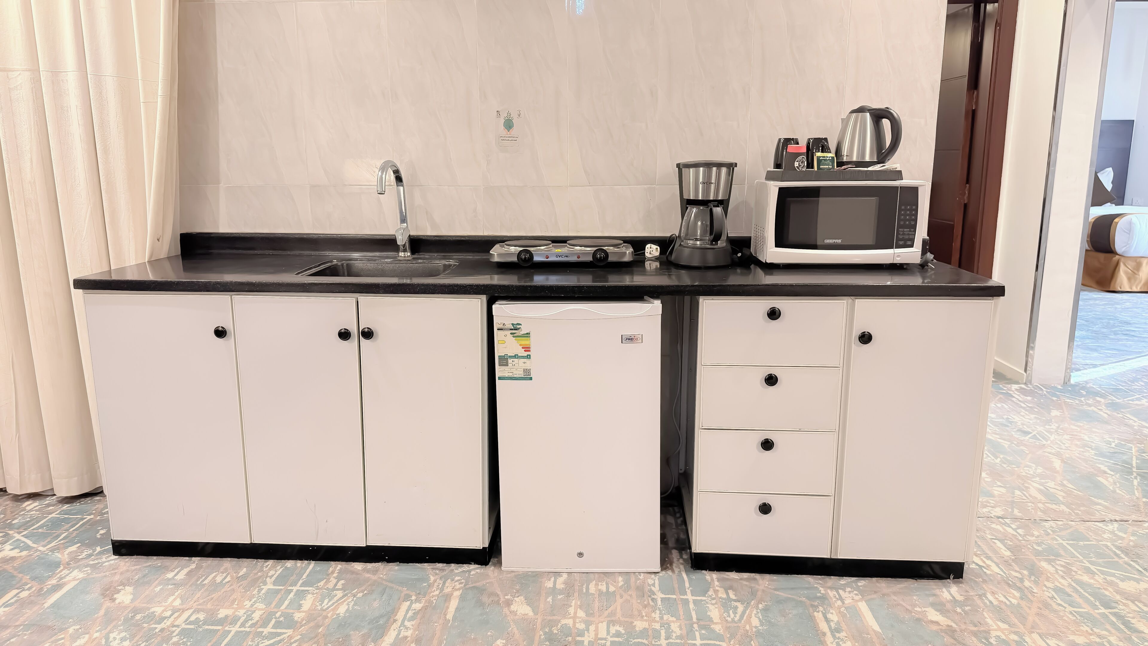 A compact kitchenette with a sink, a coffee maker, a microwave, and a refrigerator.