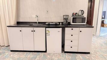 A compact kitchenette with a sink, a coffee maker, a microwave, and a refrigerator.