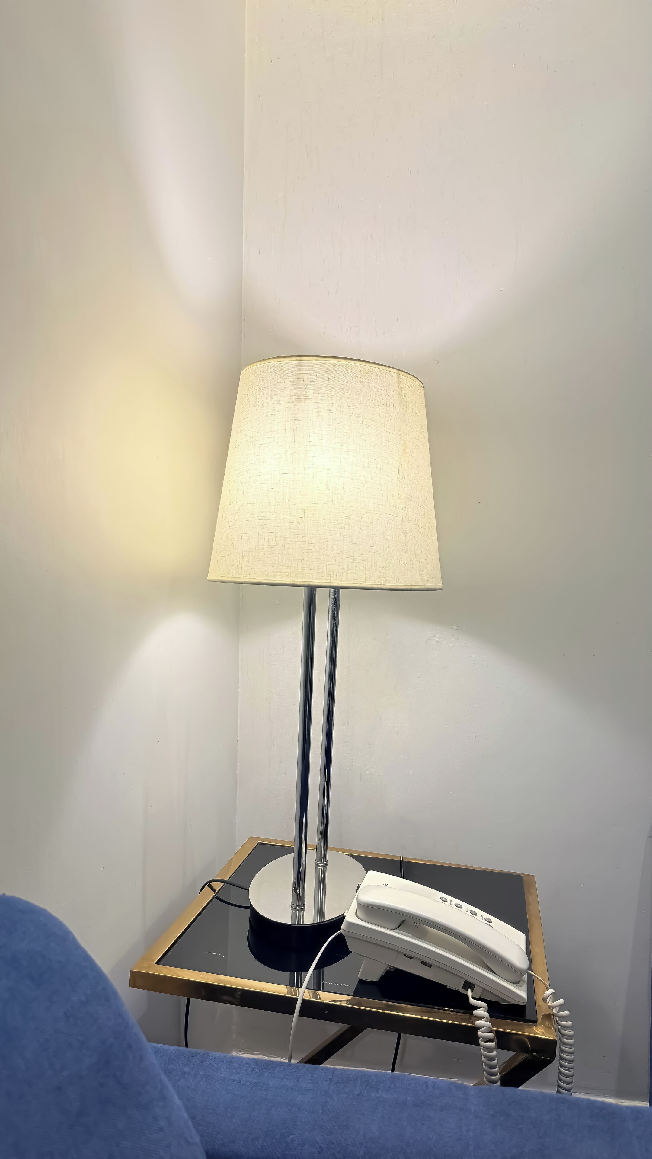 A bedside table with a lamp and a telephone.