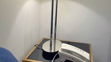 A bedside table with a lamp and a telephone.