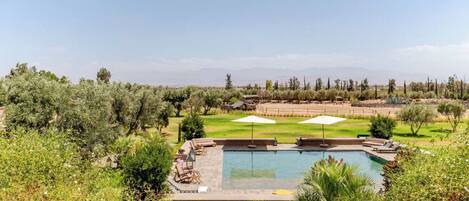 A pool area with a view of a desert landscape, surrounded by greenery and trees.