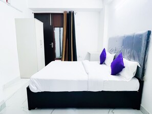 Een slaapkamer met een bed, een kledingkast, een deur en een gordijn.
