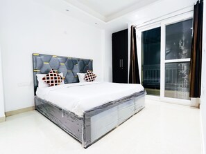 Ein Schlafzimmer mit einem Bett, einem schwarzen Kleiderschrank und einer Schiebetür zum Außenbereich.