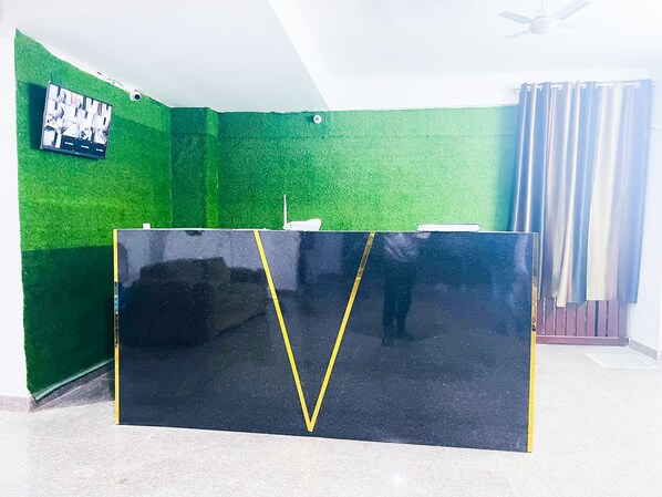 Een kamer met een groene wand, een zwart kastje en een plafondventilator.