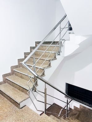 Una escalera moderna con barandas de metal y un fondo de pared blanca.