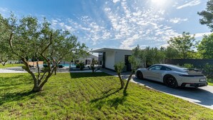 A modern house with a white exterior, a driveway, and a parked white sports car. - Luxury Matos Estate with heated pool (Zadar)
