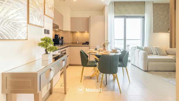A modern kitchen with a dining area, featuring a central island, chairs, and a sofa. - Manzil - 1BR in Sobha with City Views (Dubai)