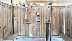Una sauna in legno con due soffioni doccia, un pannello di controllo e una panca.