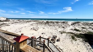 Vista sulla spiaggia con un pontile di legno e un edificio sullo sfondo.