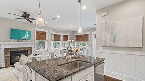 A modern kitchen with granite countertops, a built-in sink, and pendant lighting. - Sandgrass Serenity 30A  Elegant 4BR Home, Bikes, Golf Cart, Minutes to Beach (Santa Rosa Beach)