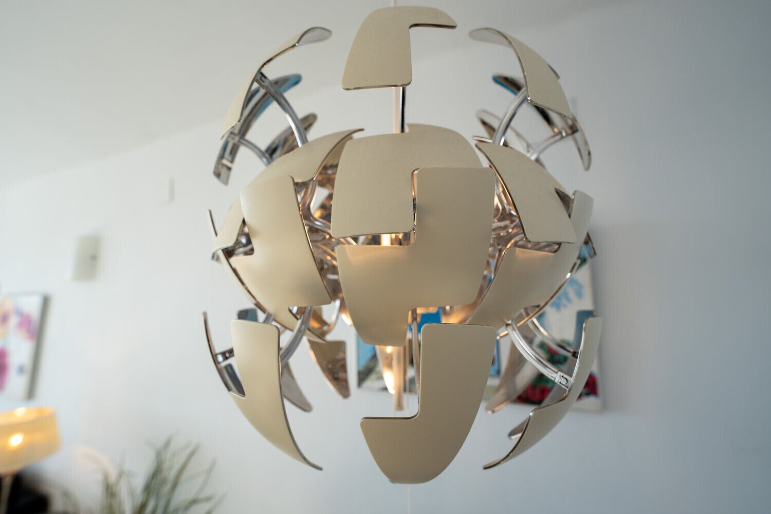 A spherical chandelier with a metallic and beige design, hanging from the ceiling.