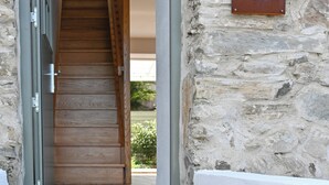 Un muro de piedra con una escalera de madera que lleva a una puerta. Un letrero en la pared dice 'the row'.