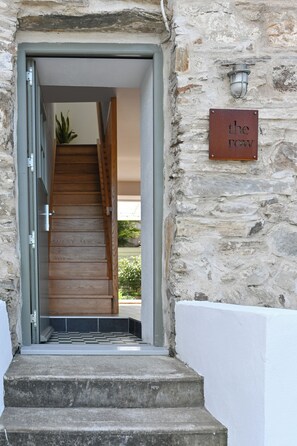 Un mur de pierre avec un escalier en bois menant à une porte. Une inscription sur le mur indique : « the row ».
