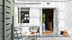 Una puerta abierta que da a una cocina, un comedor con mesa y sillas, y una ventana con lámpara colgante.