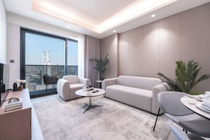A modern living room with a large window, a sofa, a coffee table, and a TV. - Stayshort - Chic 1 Bed Bedroom in JVT That Sleeps 2 With Balcony (Dubai)