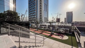 A rooftop terrace with outdoor seating, a staircase, and a view of surrounding buildings. - Stayshort - Stunning 1 Bed Bedroom in JVT That Sleeps 2 (Dubai)