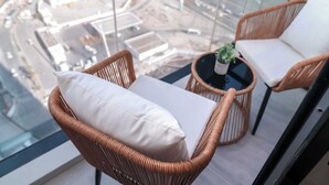 A balcony with wicker chairs and a small table, overlooking a cityscape with buildings and roads. - Stayshort - Stunning 1 Bed Bedroom in JVT That Sleeps 2 (Dubai)