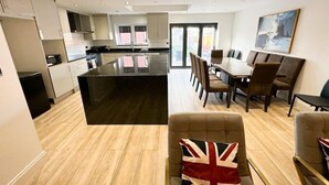 Une cuisine moderne dotée d’un îlot central, d’un coin repas avec des chaises et d’une grande fenêtre.