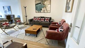 Un salon moderne avec un ensemble de canapés, une table basse et un lustre.