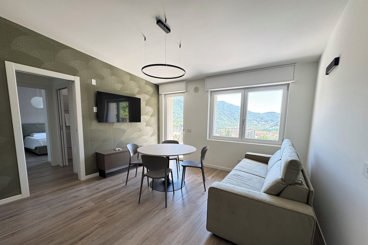Un salon moderne avec une table à manger ronde, un canapé et un téléviseur fixé au mur.