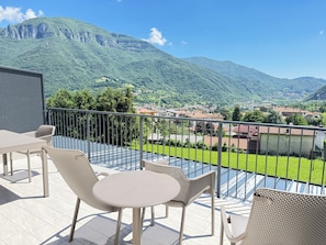 Ein Balkon mit Tisch und Stühlen, mit Blick auf eine Berglandschaft und ein Dorf.