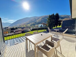 Een terras met een tafel en stoelen, met uitzicht op een bergachtig landschap.