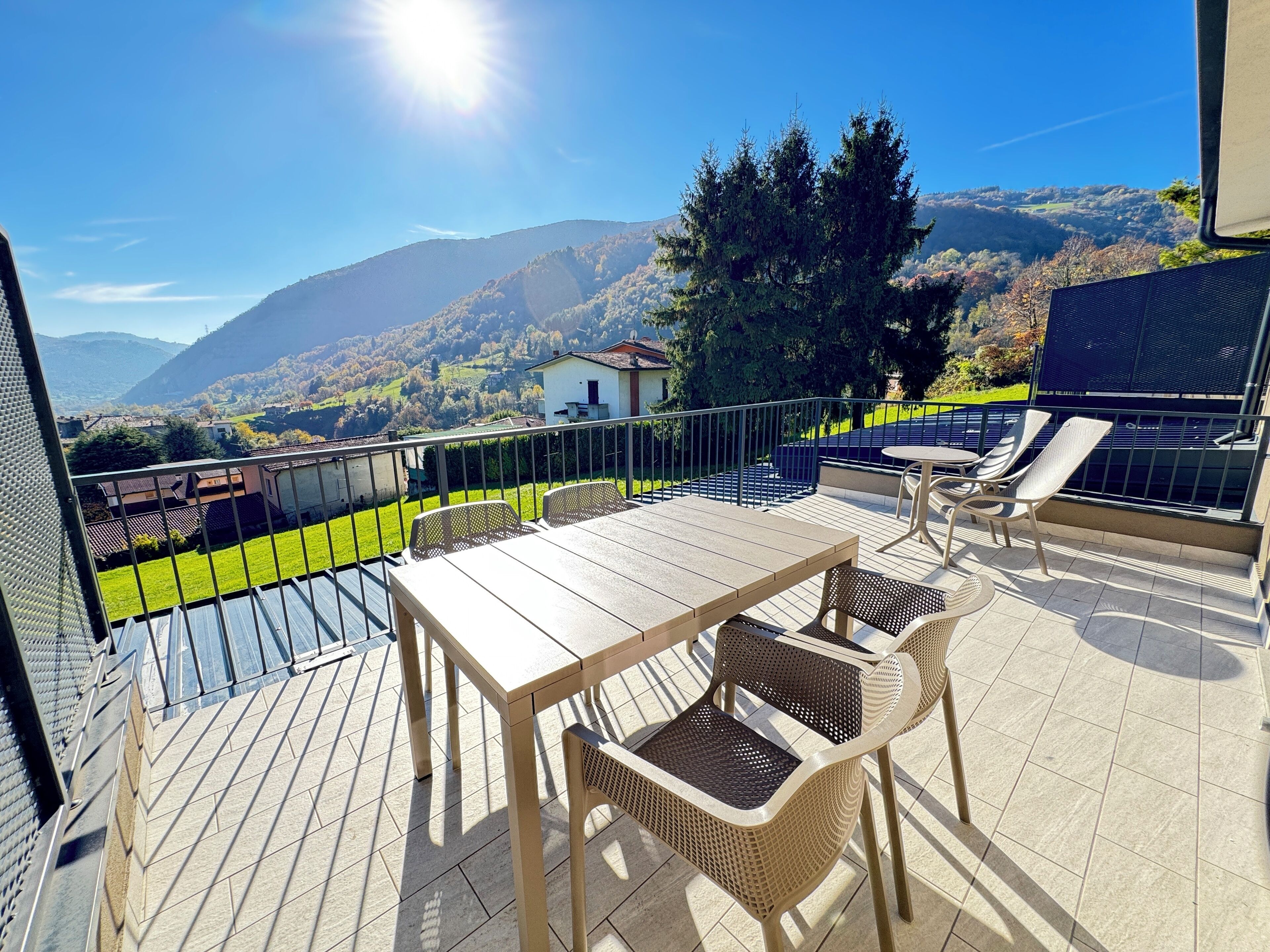 Une terrasse avec une table et des chaises, offrant une vue sur un paysage montagneux.