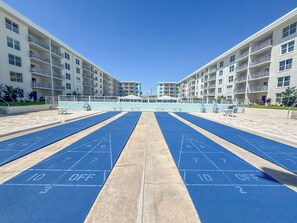 Ein Shuffleboard-Spielfeld mit freiem Blick auf ein mehrgeschossiges Wohngebäude im Hintergrund.