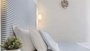 Une chambre à coucher moderne avec une tête de lit à rayures, une plante sur la table de chevet et un design minimaliste.