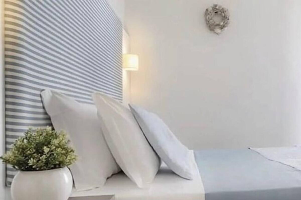 Ein modernes Schlafzimmer mit einem gestreiften Kopfteil, einer Zimmerpflanze und minimalistischem Design.