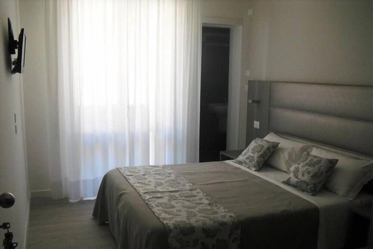 Ein Schlafzimmer mit Bett, Nachttisch, Lampe und Tür.