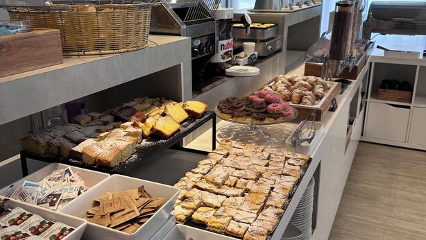 Un buffet proposant une variété de plats, notamment des pâtisseries, des desserts et des boissons.