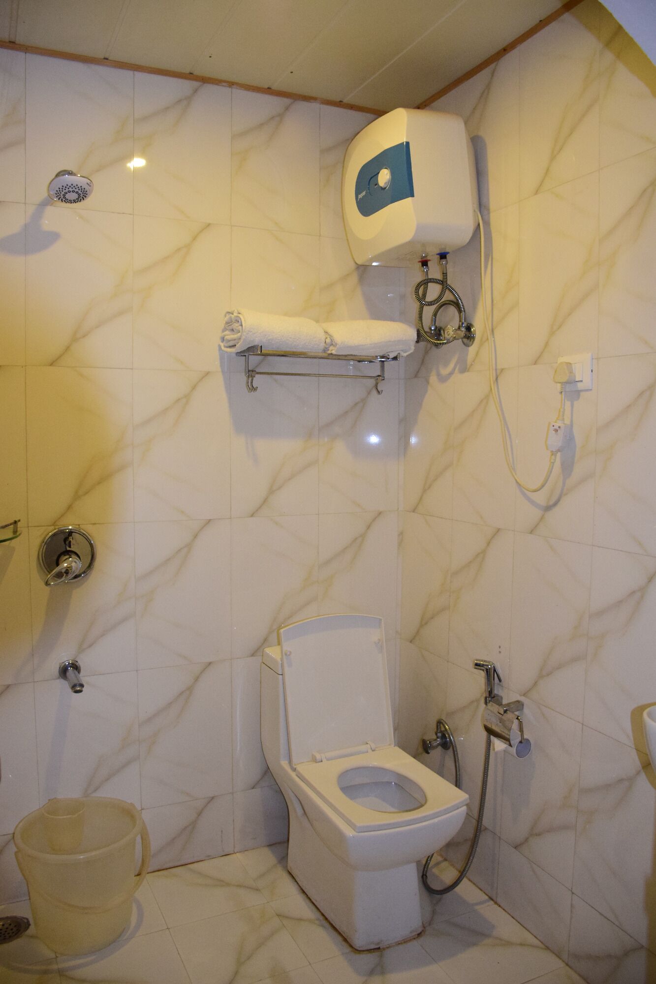 A bathroom with a toilet, shower, and a towel rack.