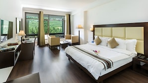 A hotel room with a large bed, a desk with a chair, a sofa, and a TV. - The Tranquil Inn (Manali)